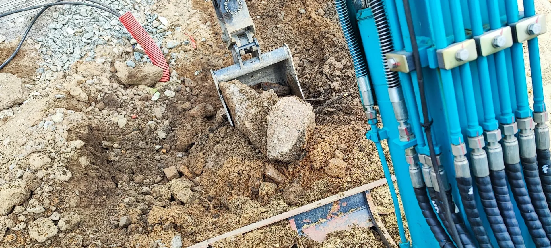 Lžíce minibagru vybírá kámen z výkopu