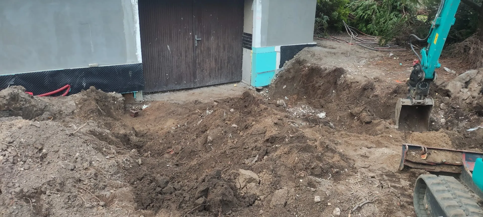 Odkopání zeminy kolem základů domu pro izolaci