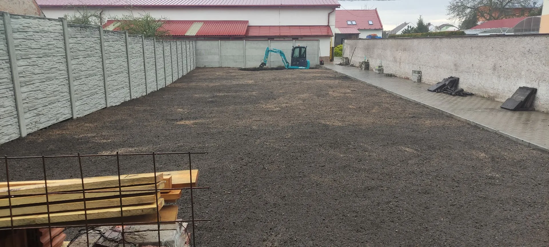 Srovnaná plocha zahrady s rozprostřenou ornicí po terénních úpravách minibagrem